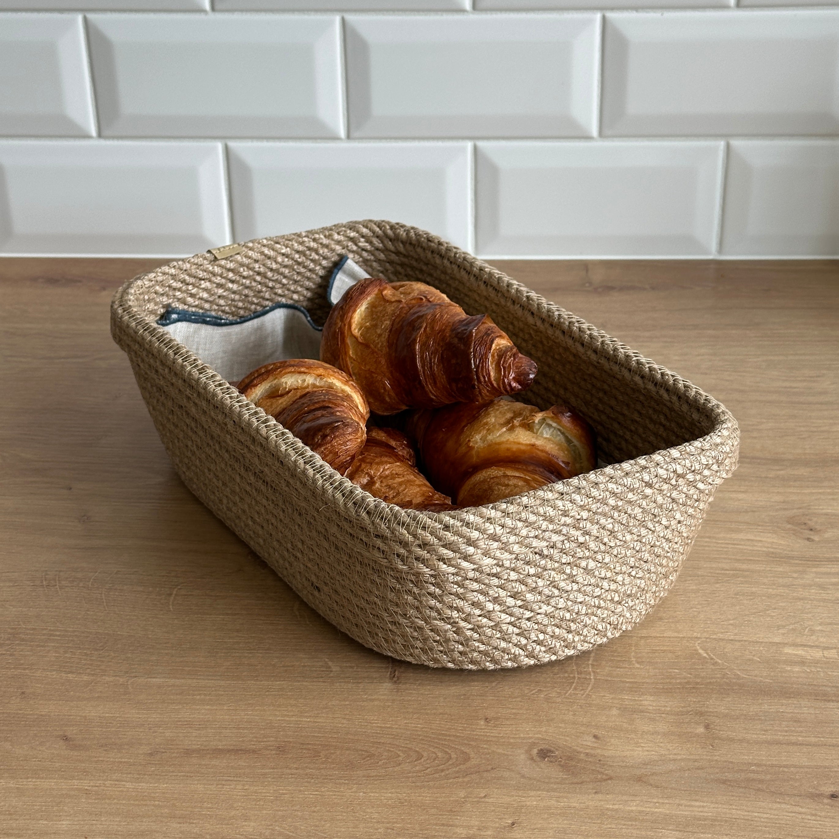 Oval kurv med ombuk, håndlavet af jute, perfekt til servering af brød og opbevaring af småting.