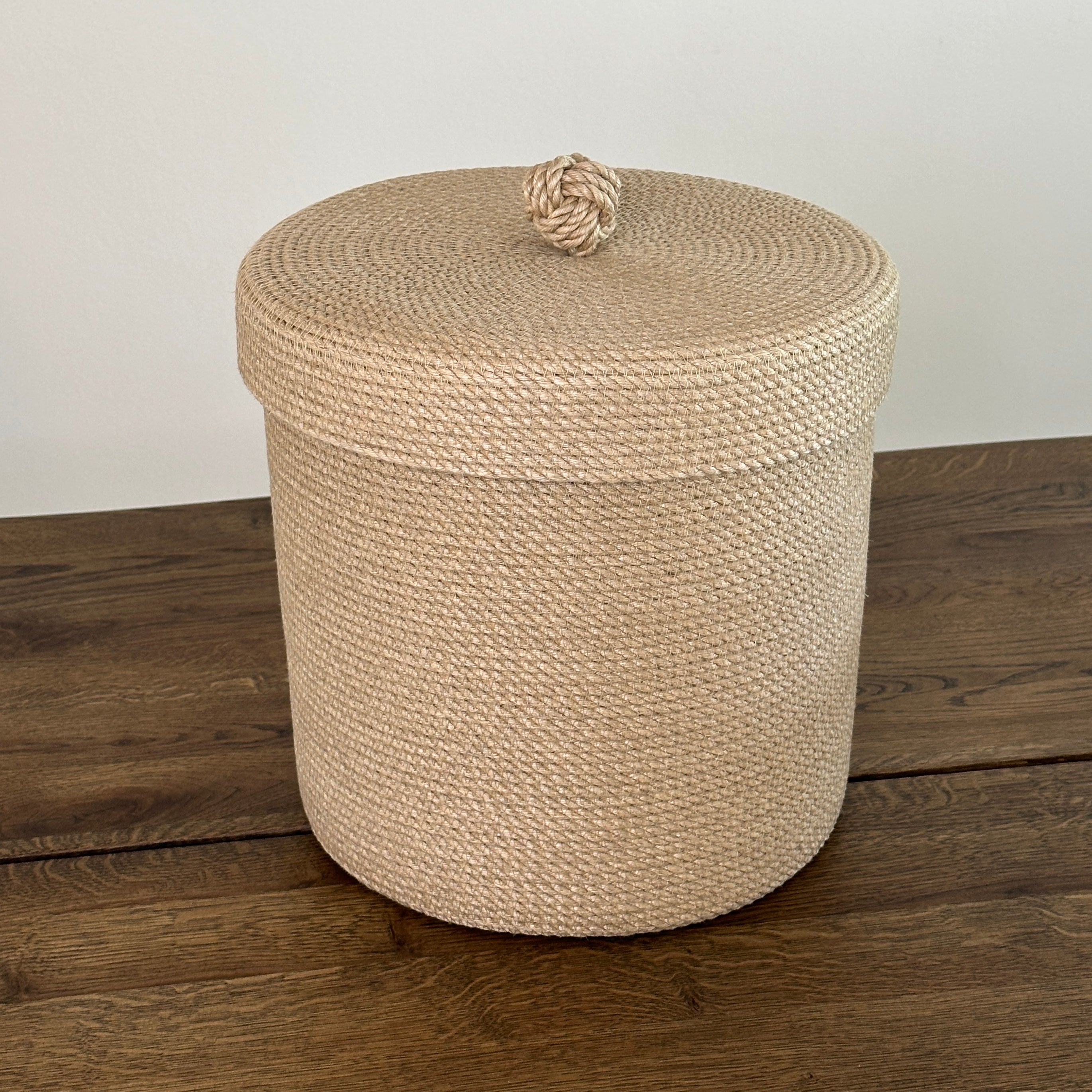 Høj jute kurv med låg og dekorativ knude, håndlavet og bæredygtig opbevaring.