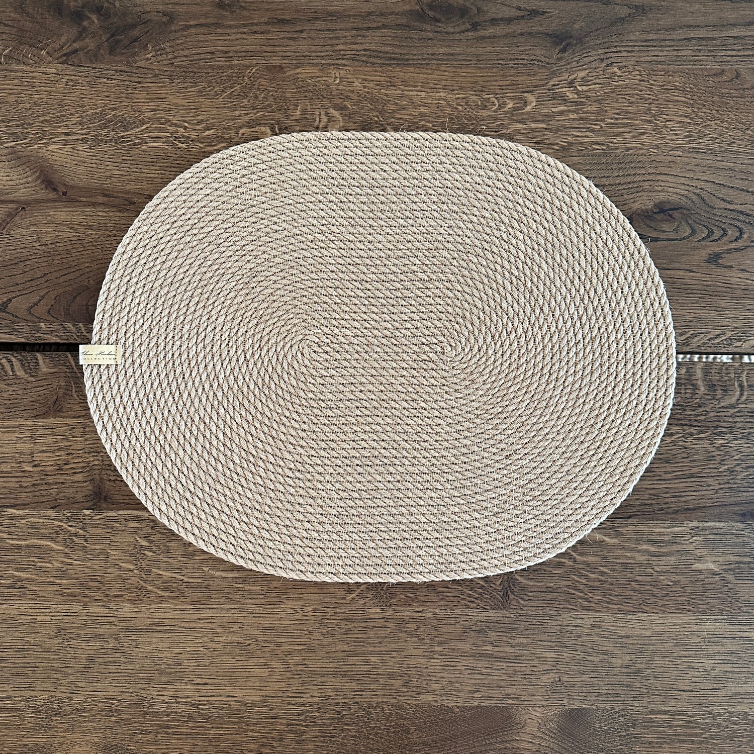 Oval håndlavet dækkeserviet i slidstærk naturlig jute, til bæredygtig og stilfuld borddækning.