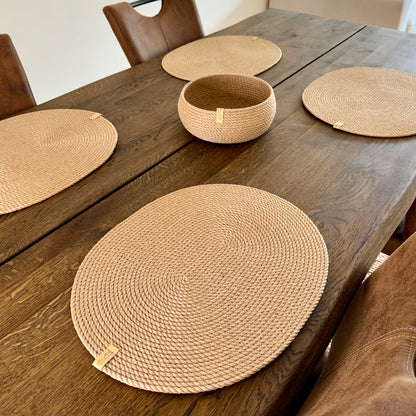 Øko-sæt til hjemmet: fire ovale dækkeservietter i jute 45×35 cm og en rund tøndeformet kurv 20×10 cm. Den gyldne nuance af jute giver hygge til både festlig og daglig borddækning.