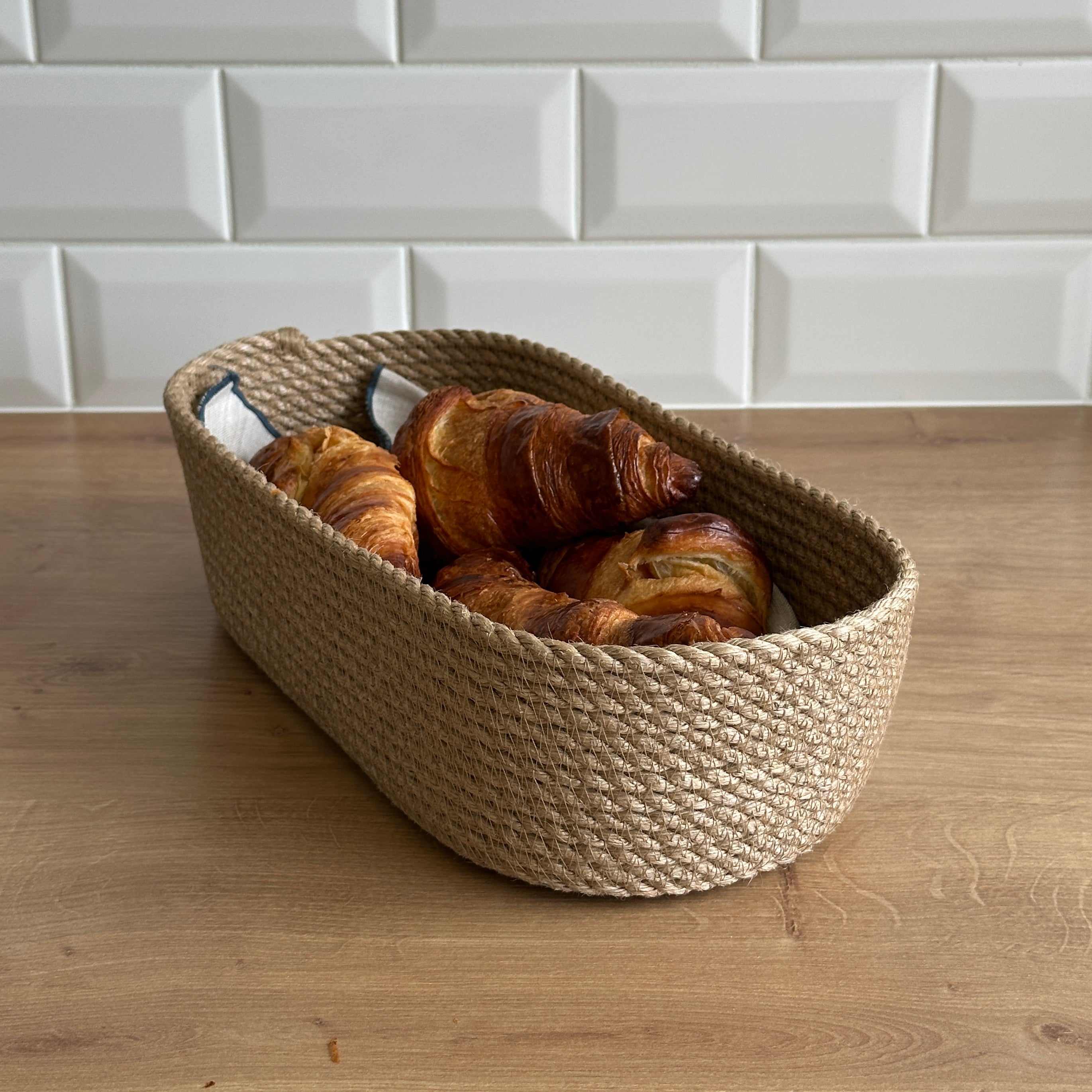 Oval håndlavet kurv af jute, praktisk til servering og opbevaring af bagværk, frugt eller småting.