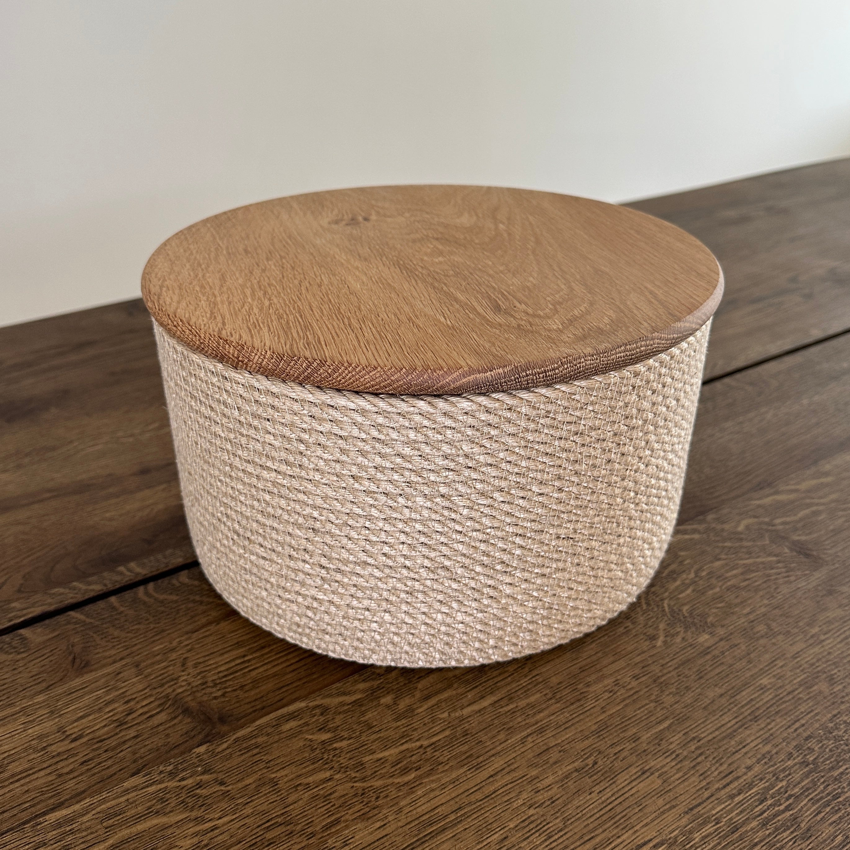 Rund håndlavet kurv af jute med låg i massivt egetræ. Et bæredygtigt og stilfuldt valg til opbevaring og servering.