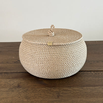 Kompakt jutekurv i tøndeform, diameter 22 cm, højde 14 cm. Fladt låg med løkkehåndtag giver både funktionalitet og stil. Håndlavet i gylden jute af premium kvalitet.