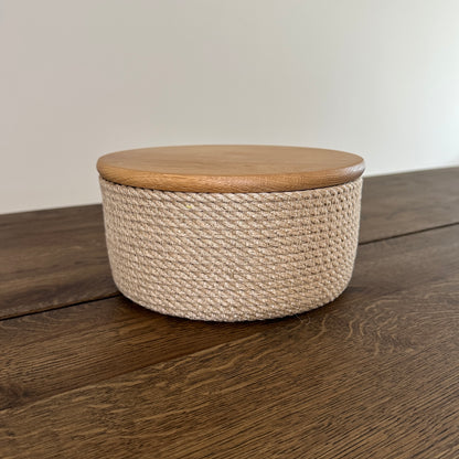 Rund kurv af naturjute med låg i eg. Håndlavet design til opbevaring og servering.