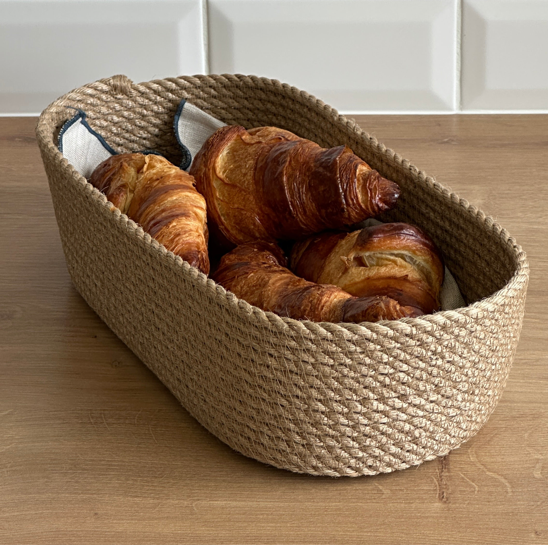 Oval kurv af naturlig jute, robust og miljøvenlig, perfekt til opbevaring og servering af brød og bagværk.