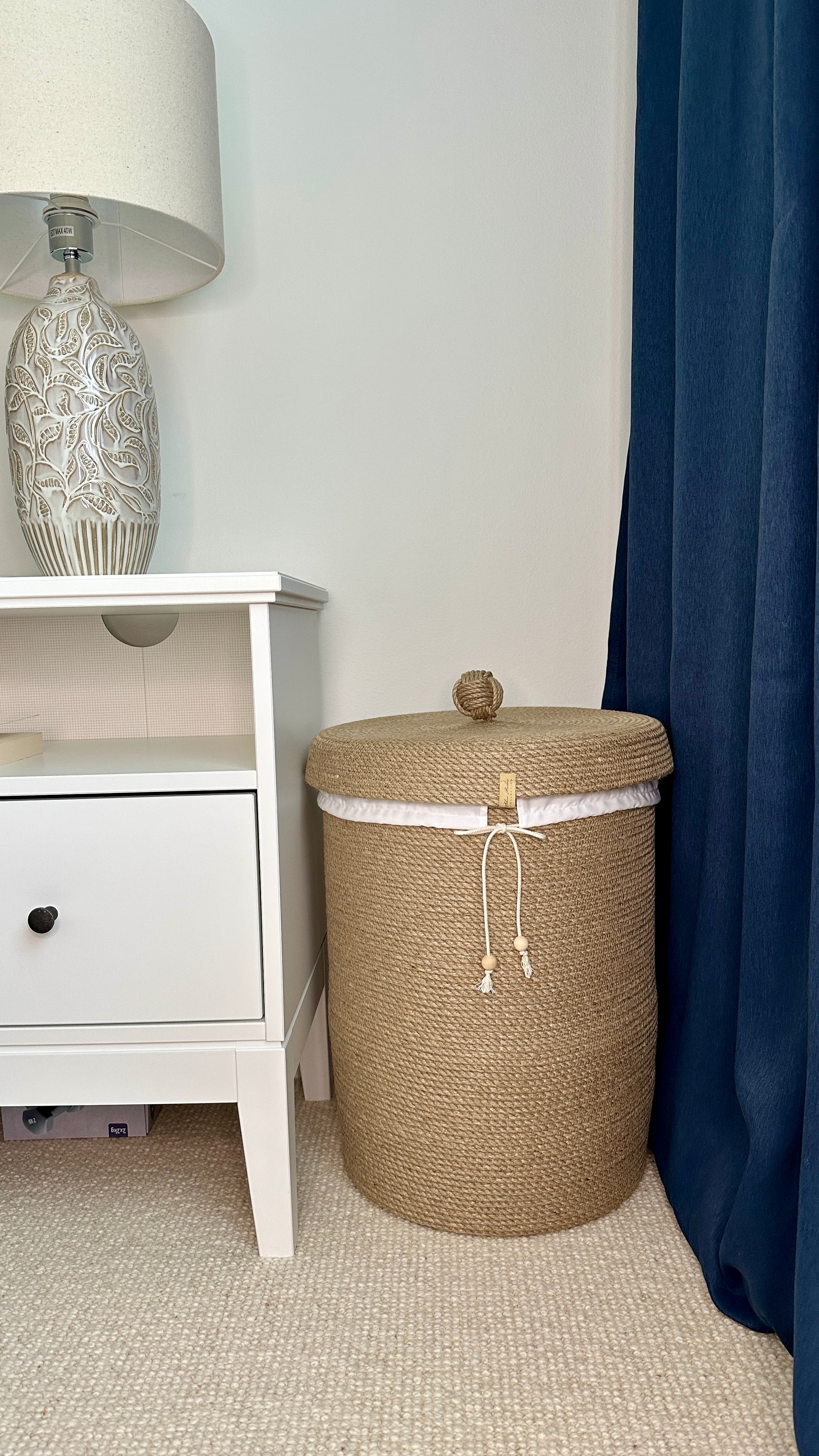 Miljøvenlig kurv i naturjute med låg – håndlavet detalje i et hyggeligt soveværelse.