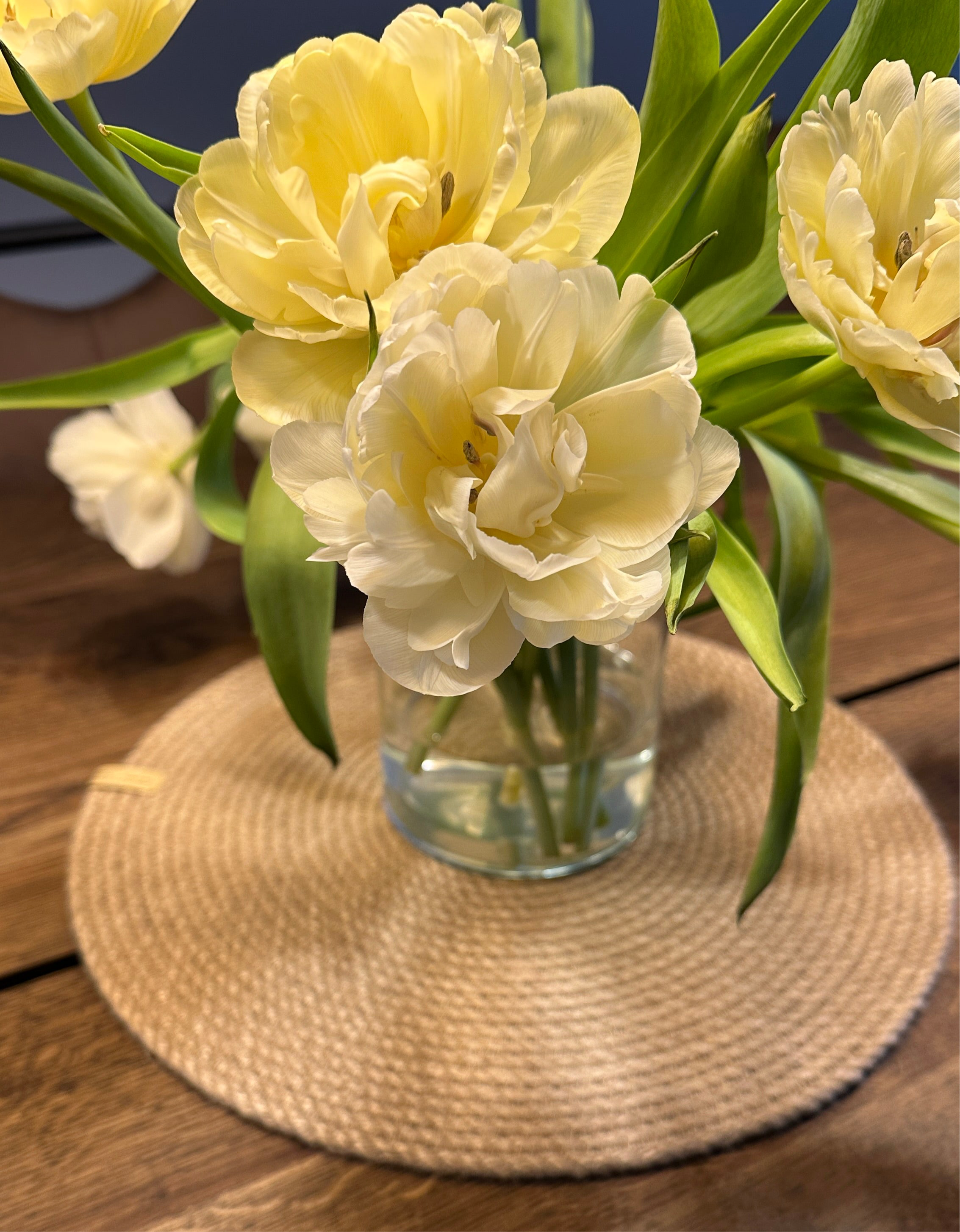 Rund håndlavet jutedækkeserviet som base for borddækning, bæredygtig dekoration til spisebordet.