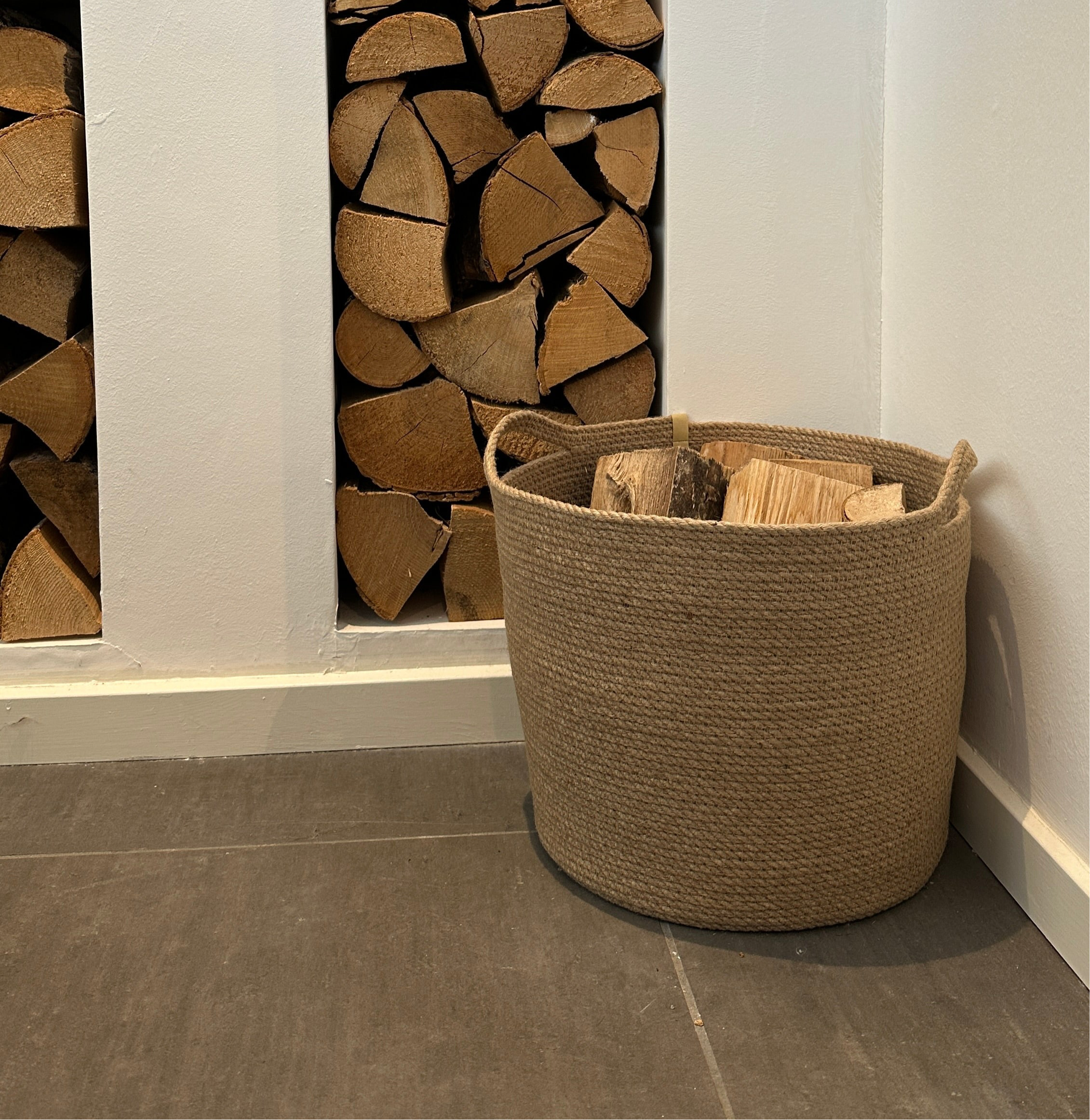 Håndlavet jutekurv med praktiske håndtag – et bæredygtigt og dekorativt valg til opbevaring af brænde ved pejsen.
