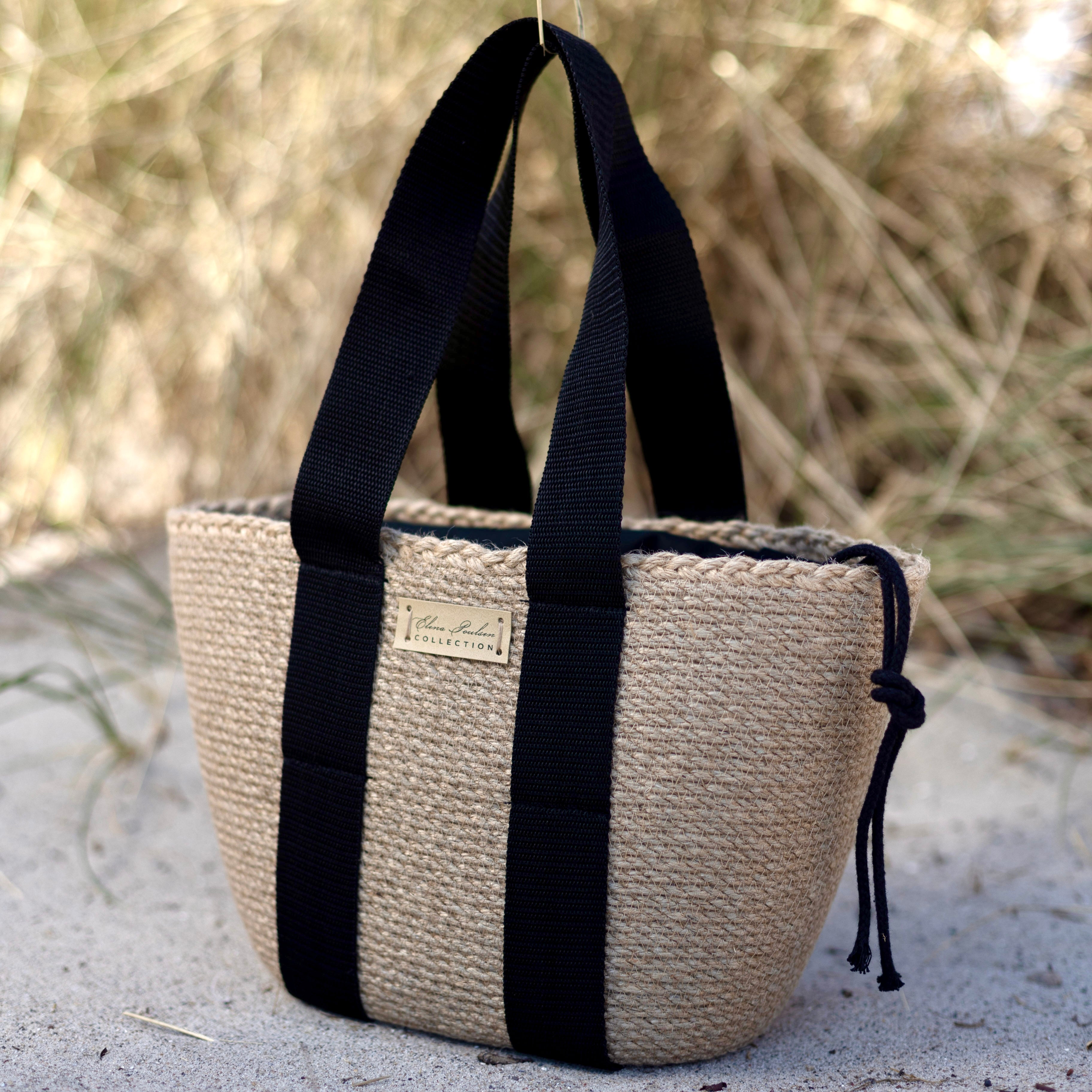 Taske af naturlig jute med sorte hanke og indvendig pose med snøre. Praktisk og stilfuldt håndværk.
