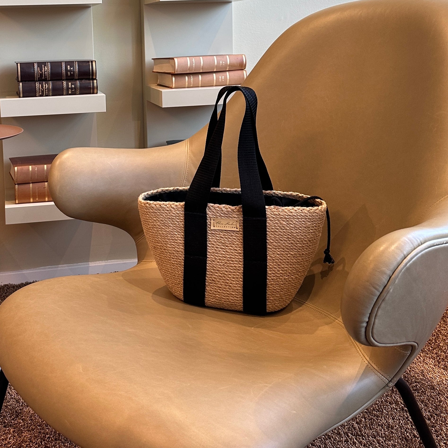 Stilfuld håndlavet jute-taske med sorte tekstilhanke og indvendig pose med snøre til sikker opbevaring.