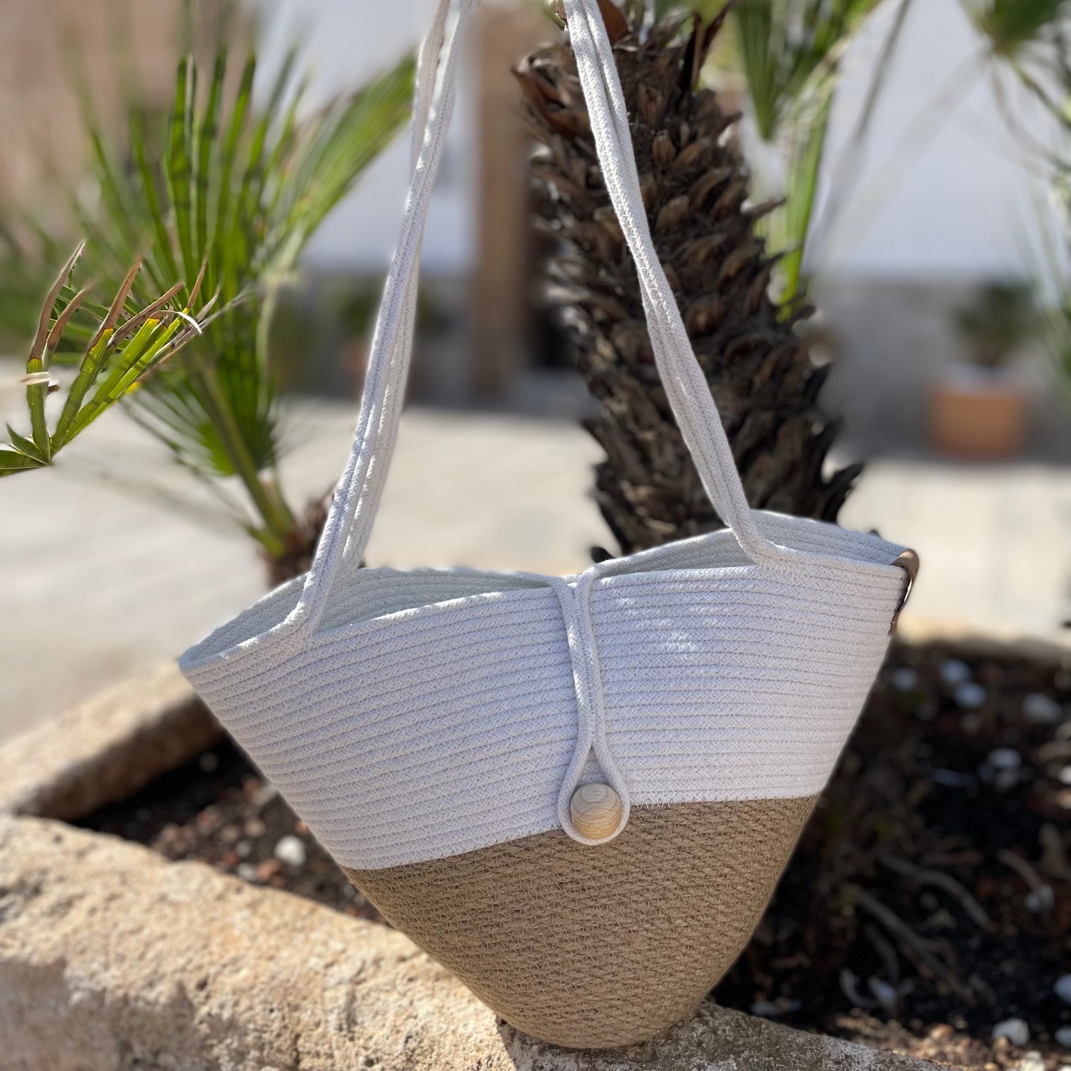 Håndlavet taske af jute og bomuldssnor med lange hanke og lukning med trækugle. Et let og stilfuldt accessory.
