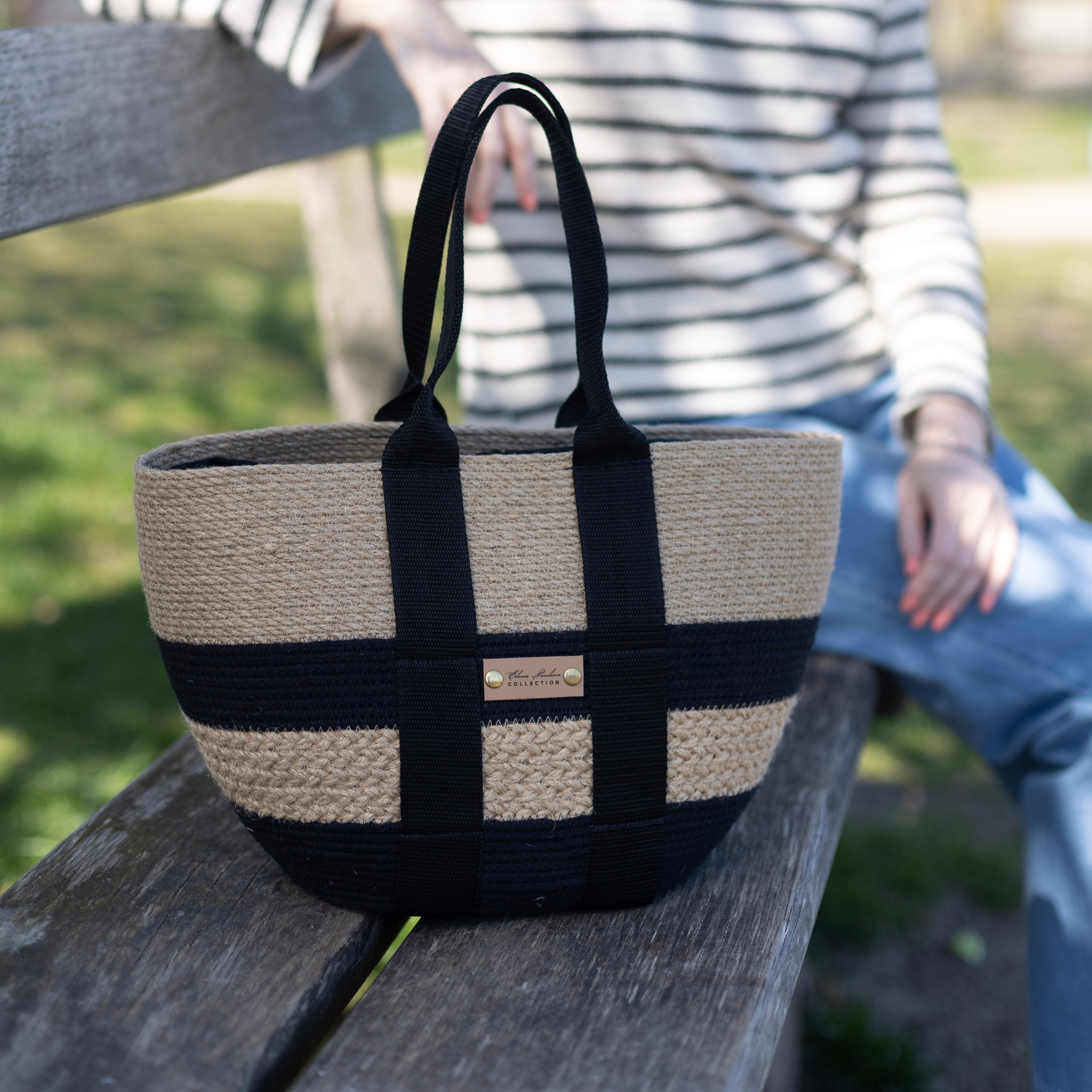 Rummelig håndlavet taske af jute og sort bomuldssnor med sorte tekstilhanke og dekorativ jutefletning.
