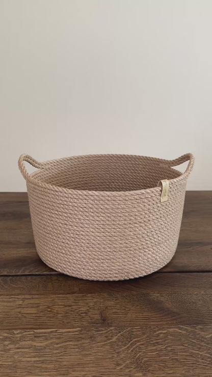 Cylinderformet jute kurv, 25 cm i diameter og 15 cm i højden, med praktiske håndtag. Det omhyggelige håndværk og premium jute fremhæver den høje kvalitet og holdbarhed.