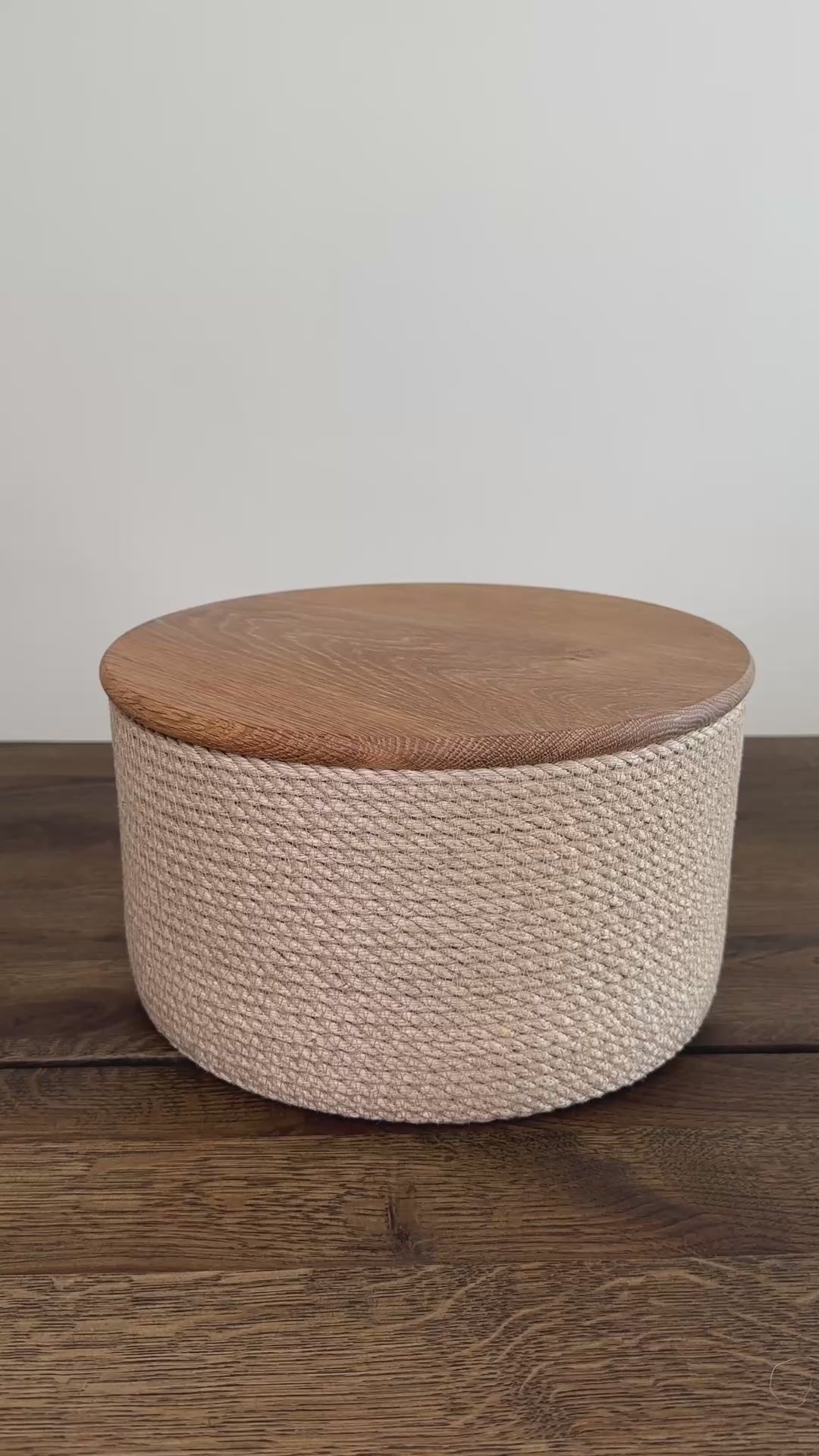 Cylinderformet jute kurv, 25 cm i diameter og 15 cm i højden, med låg af massivt egetræ. Det omhyggelige håndværk og premium jute fremhæver den høje kvalitet og holdbarhed.