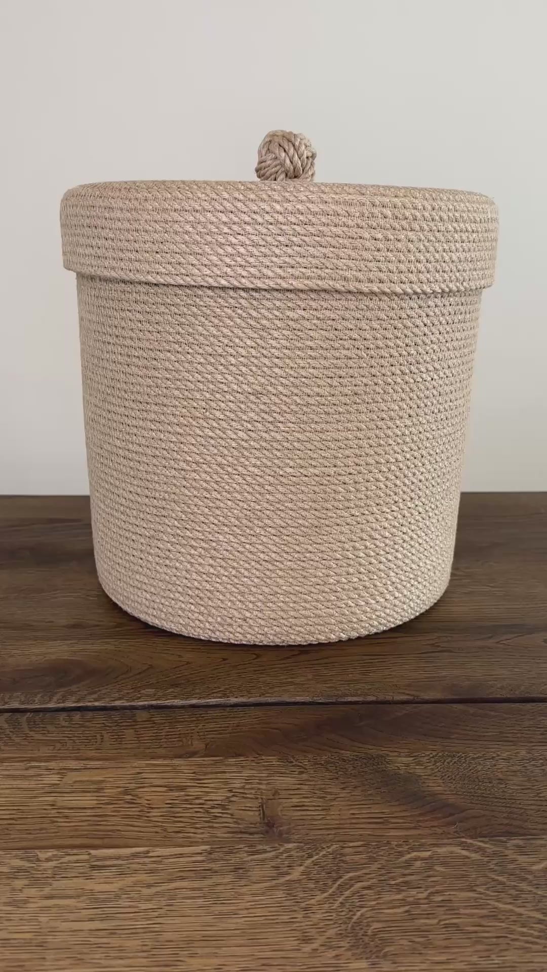 Cylinderformet jute kurv, 30 cm i diameter og 30 cm i højden, med låg og praktisk holder. Det omhyggelige håndværk og premium jute fremhæver den høje kvalitet og holdbarhed.