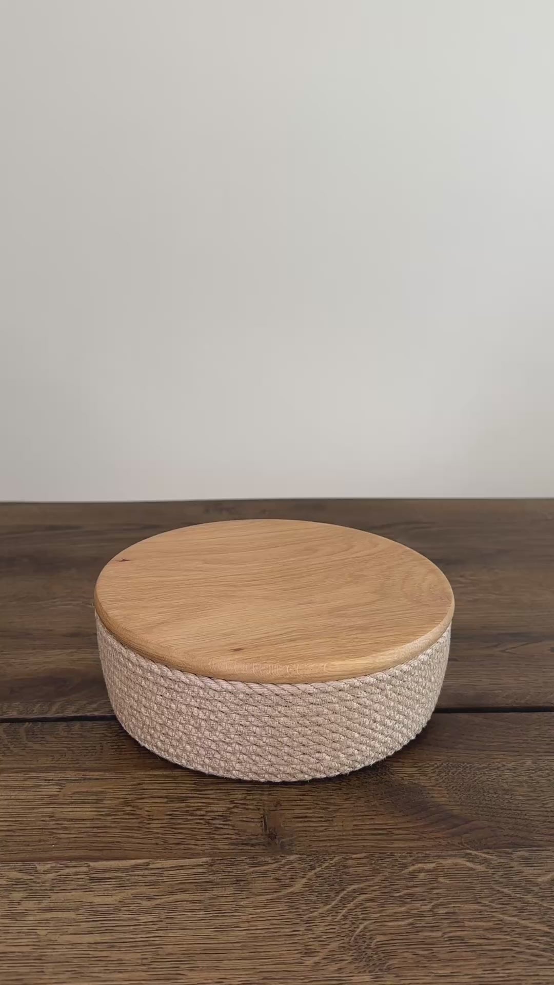 Videoen viser en lille rund jute kurv, 20×7 cm, med låg af egetræ. Den præcise udførelse og de naturlige materialer gør produktet slidstærkt og langtidsholdbart.
