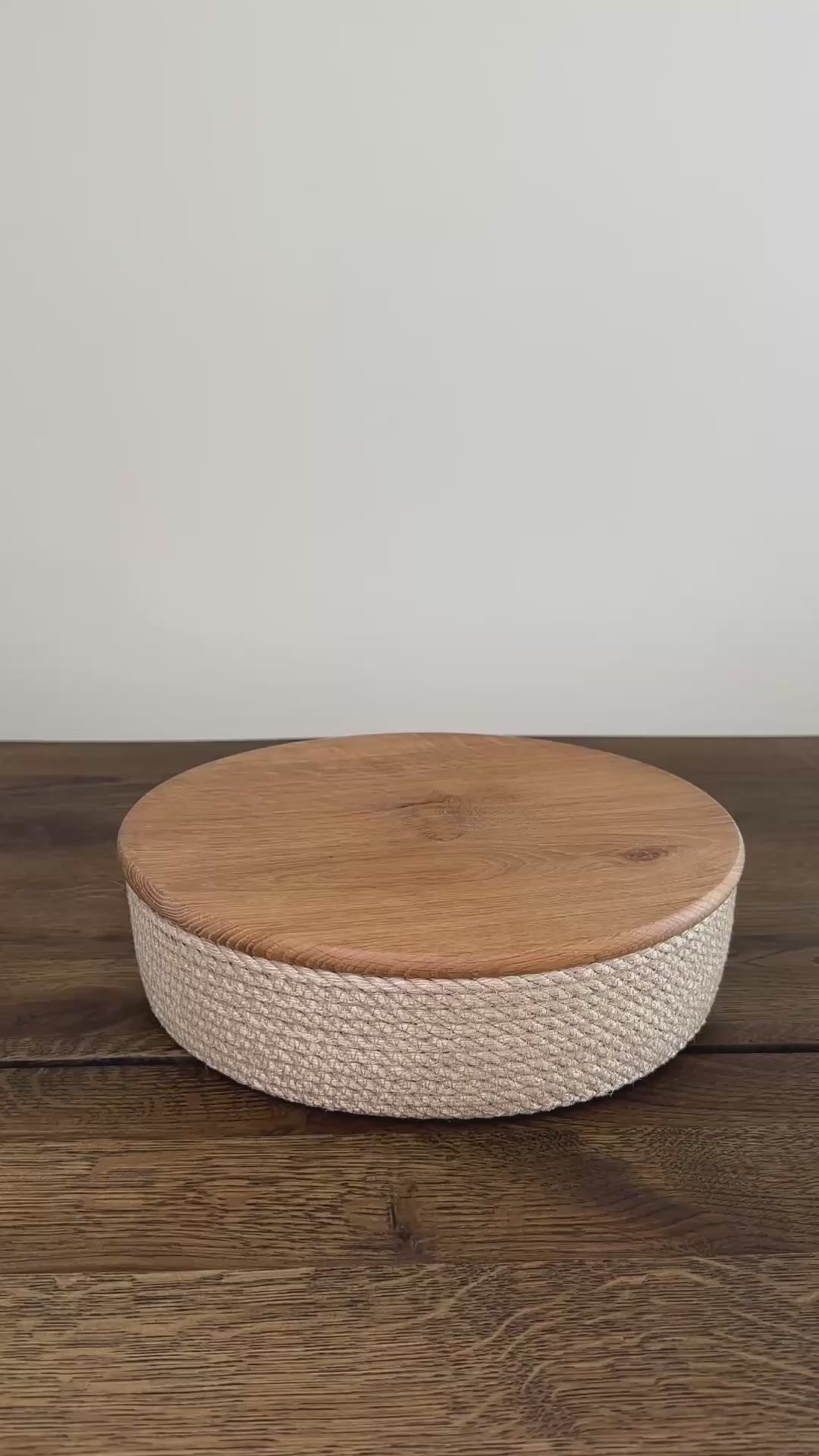 Videoen viser en rund jute kurv, 25×7 cm, med låg af egetræ. Den præcise udførelse og de naturlige materialer gør produktet slidstærkt og langtidsholdbart.