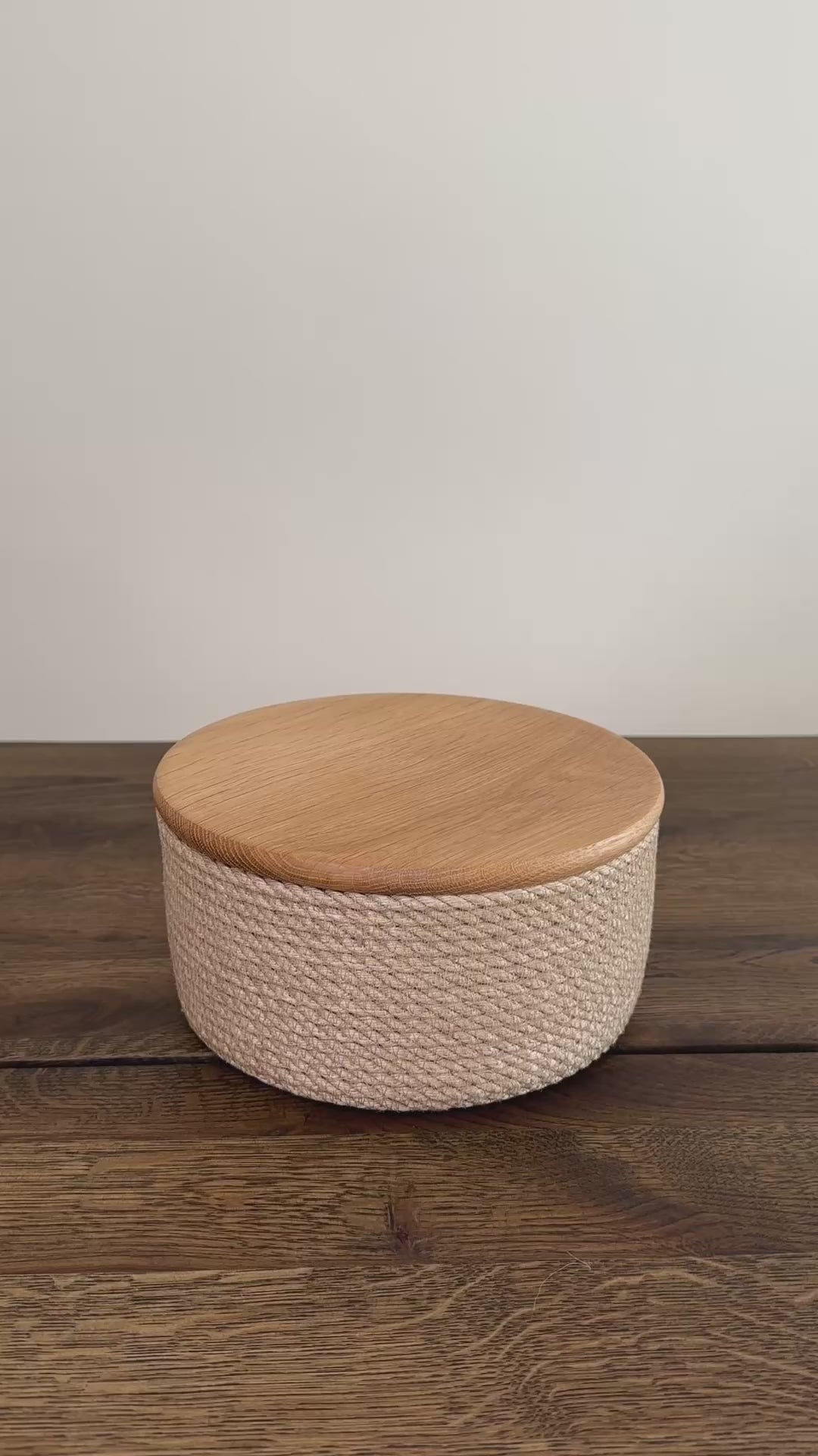 Videoen viser en jute kurv i mindre format, rund 20×10 cm, med låg af egetræ. Den præcise udførelse og de naturlige materialer gør produktet slidstærkt og langtidsholdbart.